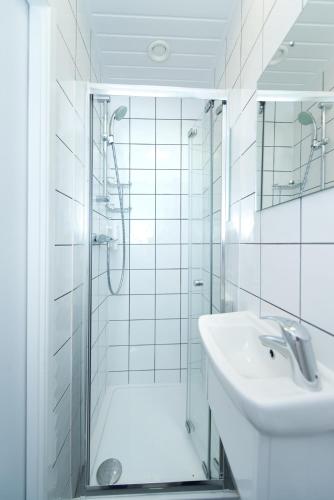a white bathroom with a shower and a sink at Angus Hotel in London