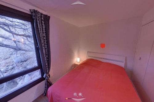 Un pequeño dormitorio con una cama roja y una ventana en Appartement 5 pièces à ISOLA 2000, en Isola 2000