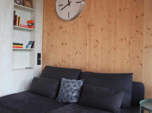 a living room with a couch and a clock on the wall at ROOTS Tiny House in Tilburg