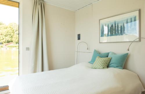 a white bed with blue pillows in a bedroom at Marina Hausboote und Seelodge in Berlin
