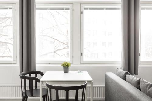 a living room with a table and two windows at Hiisi Homes Helsinki Haaga in Helsinki
