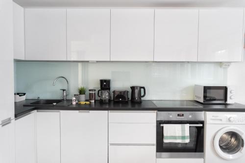 a white kitchen with a stove and a microwave at Hiisi Homes Helsinki Haaga in Helsinki