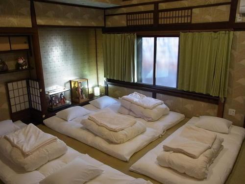 a room with four beds with white sheets and a window at Thank you so muchya Miyaco in Kyoto
