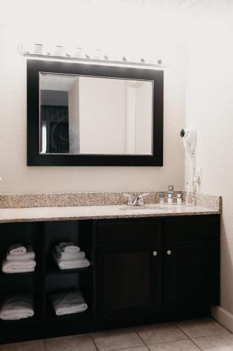 a bathroom with a sink and a mirror at Eastland Suites Hotel & Conference Ctr, Trademark by Wyndham in Bloomington