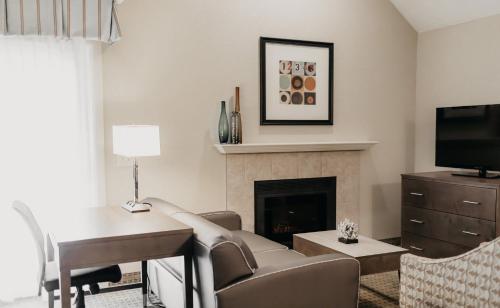 a living room with a desk and a fireplace at Eastland Suites Hotel & Conference Ctr, Trademark by Wyndham in Bloomington