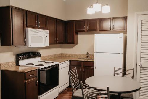 a kitchen with wooden cabinets and a white refrigerator at Eastland Suites Hotel & Conference Ctr, Trademark by Wyndham in Bloomington