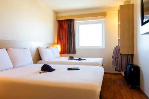 a hotel room with two beds and a window at Ibis Juarez Consulado in Ciudad Juárez