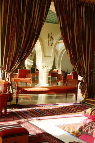 a living room with red chairs and curtains at Regency Hotel & Spa in Monastir