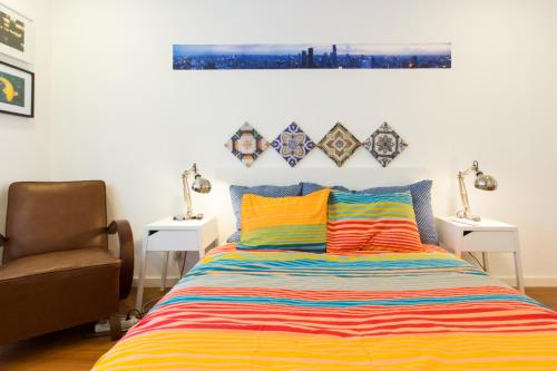 a bed with a colorful striped comforter and a chair at Cozy place in Lisbon 23 in Lisbon