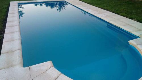 una piscina azul con reflejo de un árbol en el agua en Casa Quinta Las Pintas en Olavarría