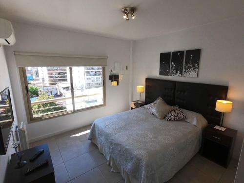 een slaapkamer met een bed en een groot raam bij Rent Apart Caballito in Buenos Aires