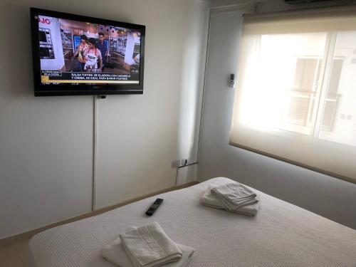 a bedroom with a bed with a television on the wall at ALIWE ( A 300 metros del Aeropuerto El Palomar) in El Palomar