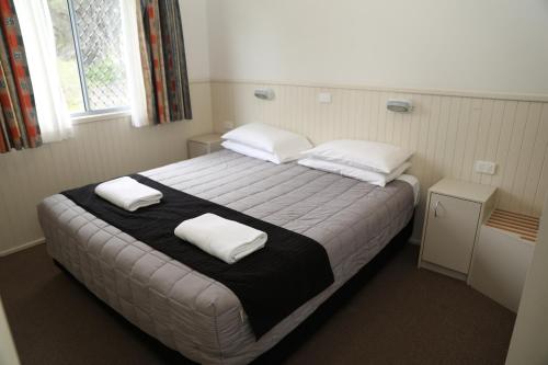 Un dormitorio con una cama grande con dos almohadas. en Corrimal Beach Tourist Park, en Wollongong