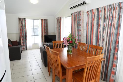 a dining room table with chairs and a vase of flowers at Corrimal Beach Tourist Park in Wollongong