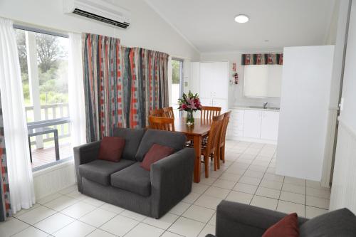 sala de estar con mesa, sofá y cocina en Corrimal Beach Tourist Park, en Wollongong
