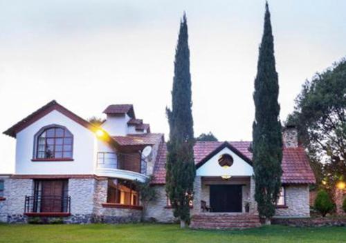 a house with two tall trees in front of it at La Mora Casa de Campo in Huasca de Ocampo