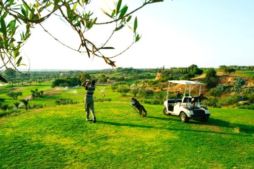 a man playing golf with a dog and a golf cart at Regency Hotel & Spa in Monastir
