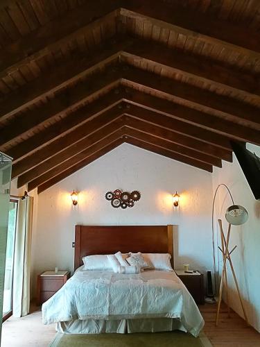 a bedroom with a large bed with a wooden ceiling at La Mora Casa de Campo in Huasca de Ocampo