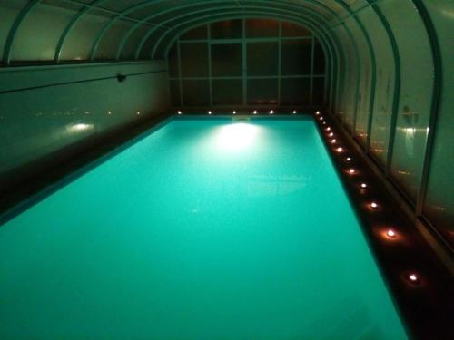 a swimming pool with blue water in a room with lights at Azure Guest House in Silveira