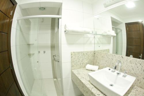 a white bathroom with a sink and a shower at Hotel Cantelle in Frederico Westphalen