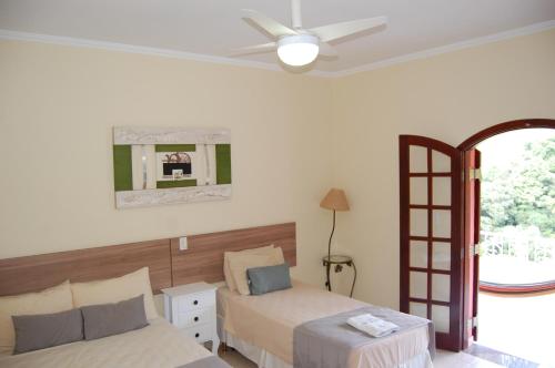 1 dormitorio con 2 camas y ventilador de techo en Pousada Nefelibatas, en Águas de Lindóia