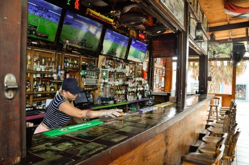 a man standing at a bar in a pub at Victoria City Hotel in Oranjestad