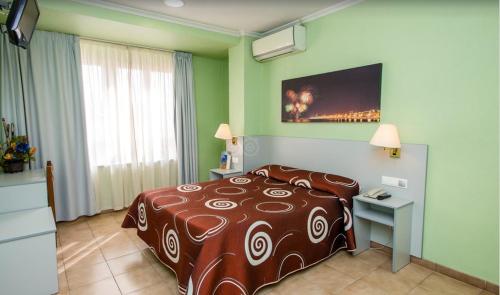 サンタ・ポラにあるHotel Patillaのベッド、テーブル、テレビが備わるホテルルームです。