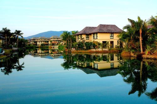 a house on the water with palm trees at Sanya Yalong Bay Villas & Spa in Sanya