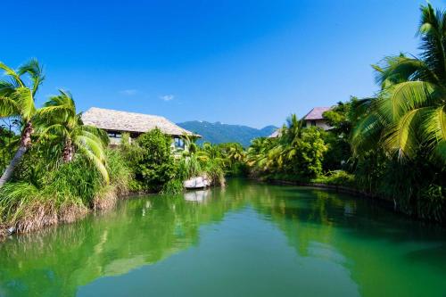 a river with palm trees in front of a house at Sanya Yalong Bay Villas & Spa in Sanya