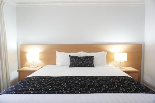 a bedroom with a large bed with two lamps at The Charles in Wagga Wagga
