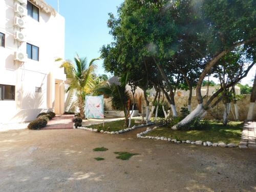 a courtyard with trees and a white building at Hotel El Perico Marinero in Río Lagartos