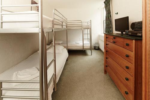 a bedroom with bunk beds with a television and a dresser at Beehive 14 in Mount Buller