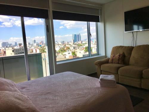 a bedroom with a bed and a couch and windows at Residencial WTC Suites México in Mexico City
