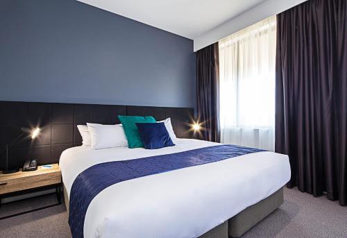 a hotel room with a large bed and a window at Mantra MacArthur Hotel in Canberra