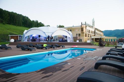 a swimming pool with chairs and a tent in the background at Altai Palace Hotel in Manzherok