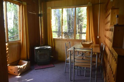 a room with a table and chairs and a wood stove at Hostal y Cabañas Vientos del Sur in Puerto Ingeniero Ibáñez