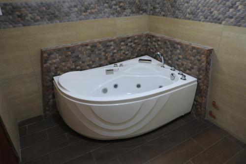 y baño con bañera y pared de azulejos. en Hotel Vicente de la Vega en Chiclayo