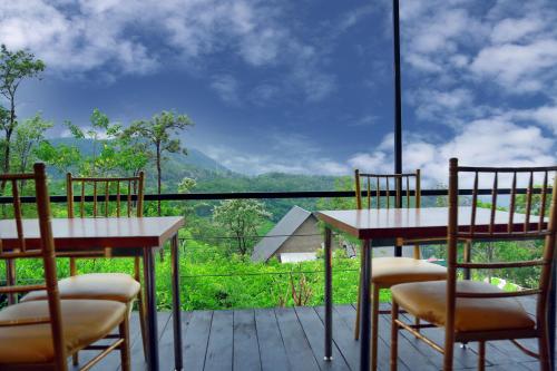 a balcony with two tables and chairs and a view at Box on clouds in Ella