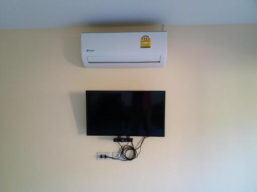 a television on a wall with a air conditioner at Palm Kaew Resort Krabi in Krabi