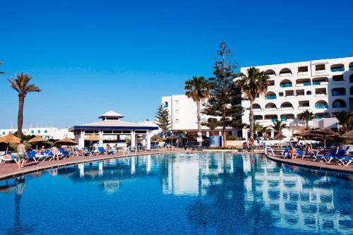 a large swimming pool with chairs and a hotel at Regency Hotel & Spa in Monastir