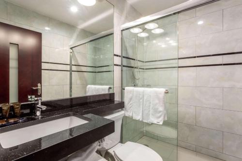 a bathroom with a toilet and a sink and a mirror at The L Hotel in Brooklyn