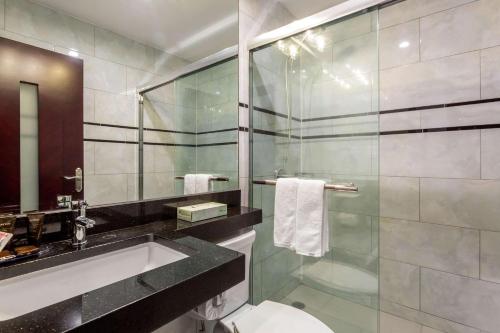 a bathroom with a sink and a glass shower at The L Hotel in Brooklyn
