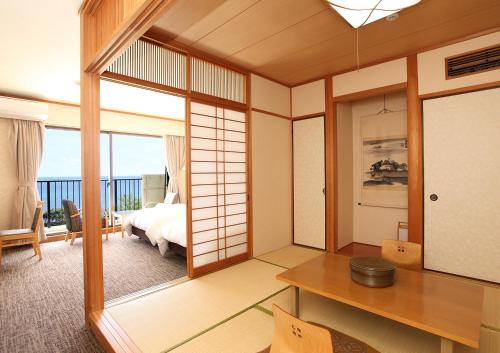 a room with a bedroom and a bed and a table at Tsushima Grand Hotel in Tsushima