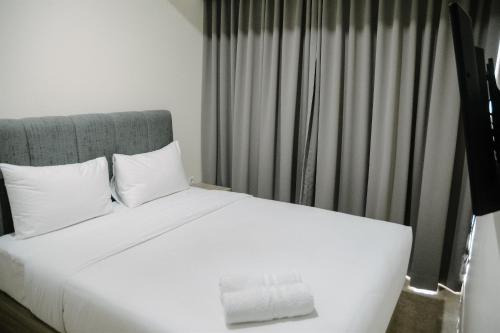 Una cama con sábanas blancas y almohadas en una habitación. en 2BR Deluxe and Modern Menteng Park Apartment By Travelio, en Yakarta