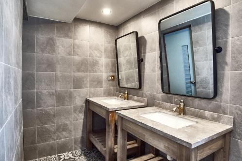 a bathroom with two sinks and two mirrors at 翠安儂風旅 in Taitung City