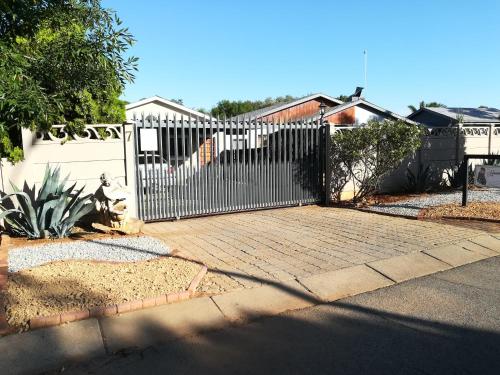 a white gate in a yard with a driveway at The Hancock Inn in Klerksdorp
