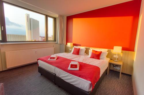 a hotel room with a large bed with an orange wall at Biendo Hotel in Chemnitz