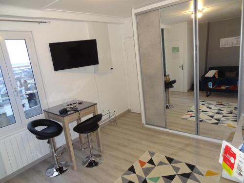 een woonkamer met twee krukken en een televisie aan de muur bij L'ESTUAIRE in Le Havre