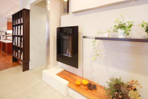 a living room with a fireplace and a television on a wall at Hotel Garden Square Shizuoka in Shizuoka