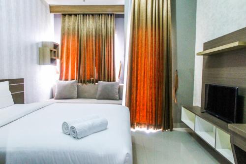 a bedroom with a large white bed and a television at New Studio The Oasis Apartment By Travelio in Cikarang